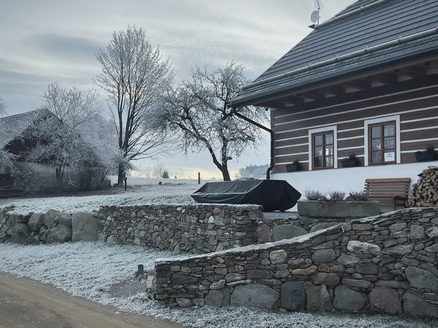Chalupa a kamenná zídka v jinovatce, zamrzlé stromy
