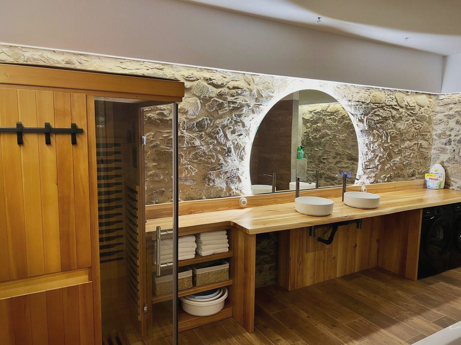 Dřevěná sauna s prosklenými dveřmi vedle umyvadel